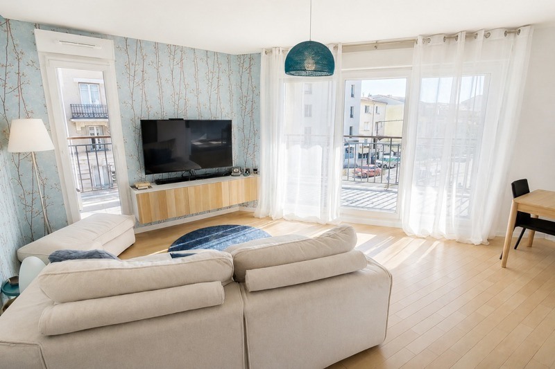 Séjour de l'appartement avec baies vitrées ouvrant sur la terrasse et parquet clair
