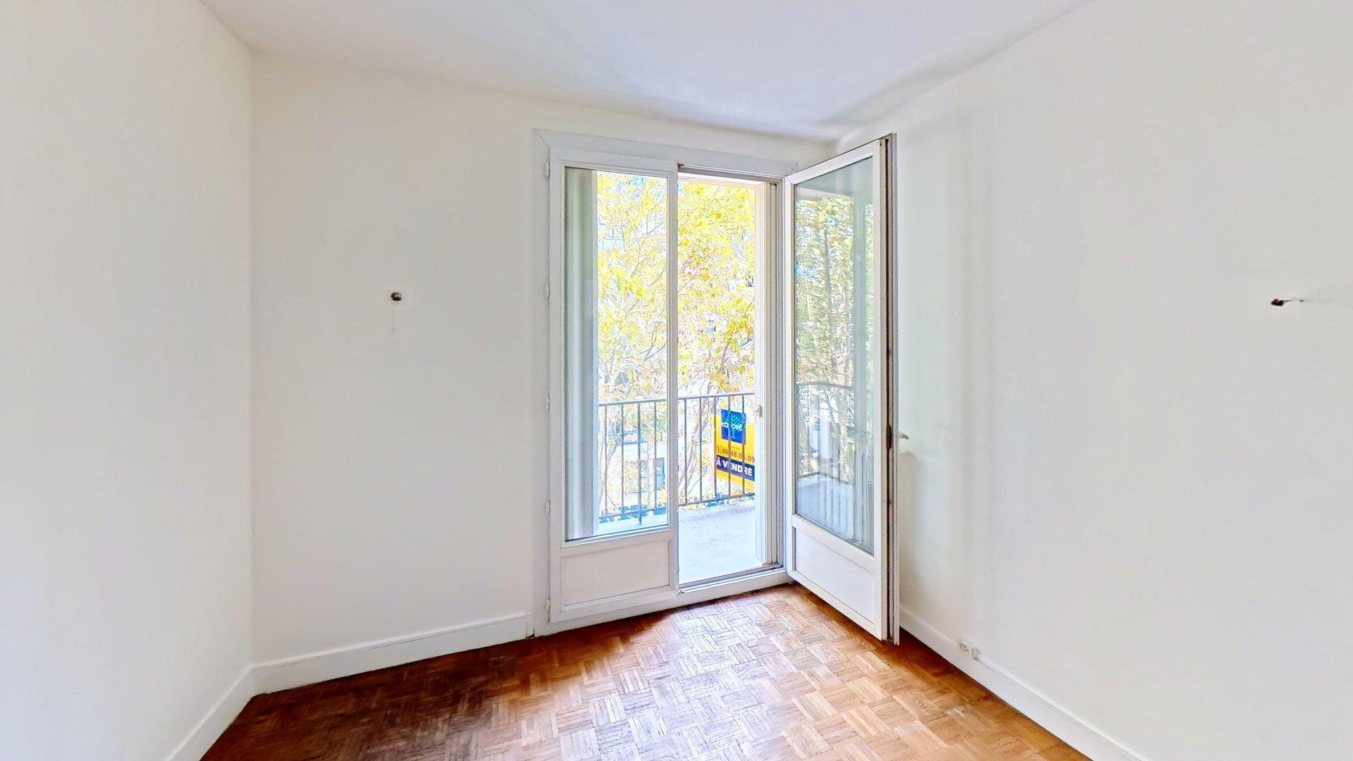 Chambre vide avec porte-fenêtre donnant sur le balcon