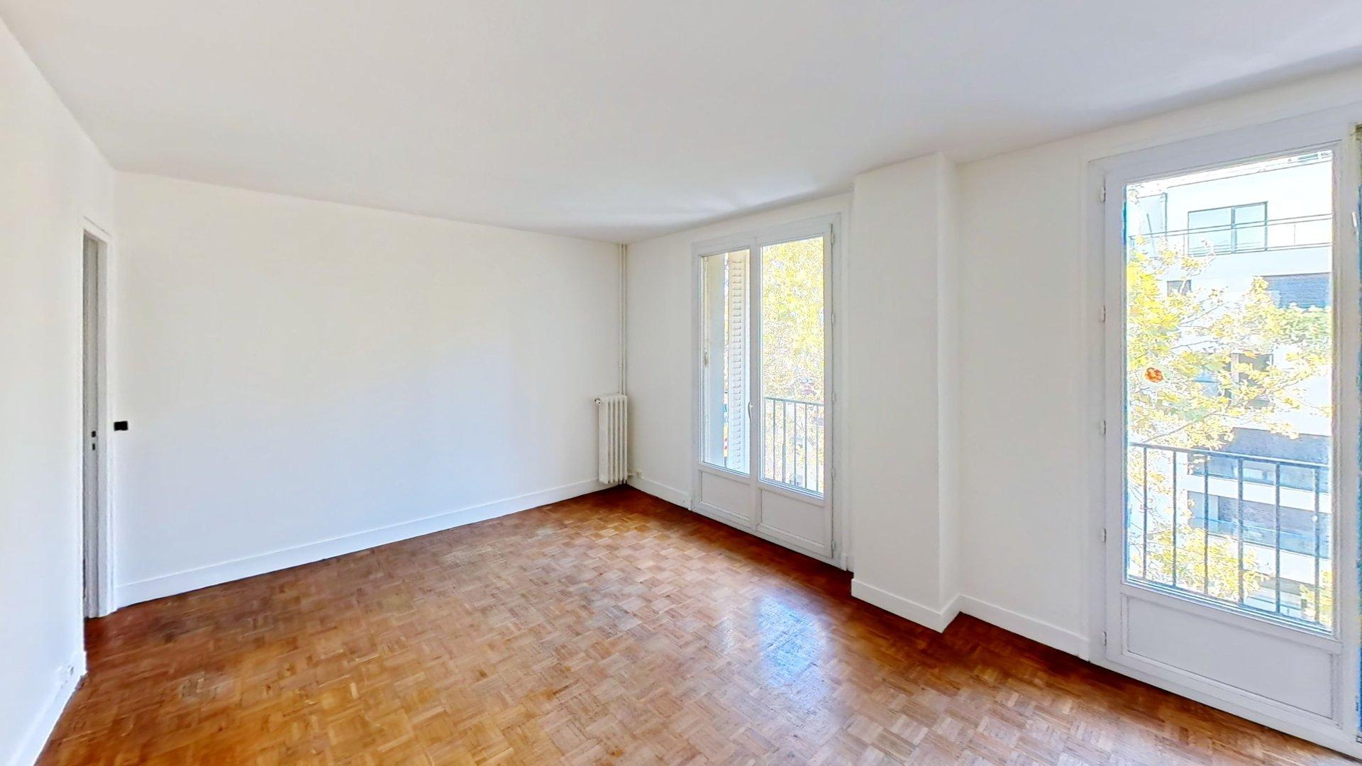 Séjour lumineux avec parquet et deux ouvertures